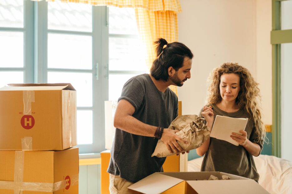 man and woman looking papers while packing